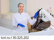 Woman doctor displaying machine for laser hair removal. Стоковое фото, фотограф Яков Филимонов / Фотобанк Лори