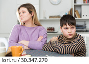 Upset mother and unhappy son sitting after quarrel indoors. Стоковое фото, фотограф Яков Филимонов / Фотобанк Лори