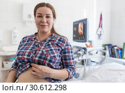 Беременная женщина довольная результатом УЗИ. Смоделированная фотография плода на экране монитора. Стоковое фото, фотограф Кекяляйнен Андрей / Фотобанк Лори