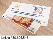 Конверт со счетом и деньги на оплату квартиры и услуг ЖКХ. Единый платежный документ, счет за жилищно-коммунальные услуги Мособлеирц (2019 год). Редакционное фото, фотограф Кузин Алексей / Фотобанк Лори