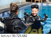 Woman getting first experience with scuba diving under the guidance of experienced recreational diving instructor in swimming pool. Стоковое фото, фотограф Matej Kastelic / Фотобанк Лори