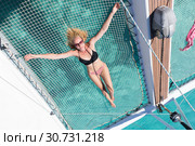 Woman relaxing on a summer sailing cruise,lying in hammock of luxury catamaran near picture perfect white sandy beach on Spargi island in Maddalena Archipelago, Sardinia, Italy. Стоковое фото, фотограф Matej Kastelic / Фотобанк Лори