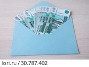 On the table a blue envelope with a Russian banknotes in denominations of one thousand rubles. Стоковое фото, фотограф Катерина Белякина / Фотобанк Лори