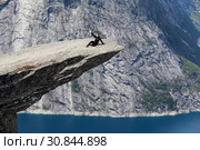 Женщина сидит на выступающем утесе Язык Тролля (Trolltunga). Odda, Hordaland, Норвегия. Стоковое фото, фотограф Кекяляйнен Андрей / Фотобанк Лори