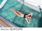 Woman relaxing on a summer sailing cruise,lying in hammock of luxury catamaran near picture perfect white sandy beach on Spargi island in Maddalena Archipelago, Sardinia, Italy. Стоковое фото, фотограф Matej Kastelic / Фотобанк Лори