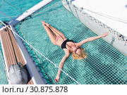 Woman relaxing on a summer sailing cruise,lying in hammock of luxury catamaran near picture perfect white sandy beach on Spargi island in Maddalena Archipelago, Sardinia, Italy. Стоковое фото, фотограф Matej Kastelic / Фотобанк Лори