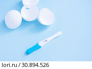 Infertility. Negative pregnancy test and eggshell on blue. Стоковое фото, фотограф Papoyan Irina / Фотобанк Лори