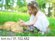 Happy little girl pets the cat in summer outdoors. Стоковое фото, фотограф ivolodina / Фотобанк Лори