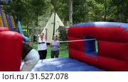 Emotional bearded guy tied with rope to his African friend competing to collect hoops on inflatable playground. Стоковое видео, видеограф Яков Филимонов / Фотобанк Лори