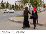 Чечня, Грозный. Две молодые женщины идут по проспекту Ахмата Кадырова в пасмурную погоду. Two young women are walking along Akhmat Kadyrov Avenue in cloudy weather. (2015 год). Редакционное фото, фотограф Ольга Шуклина / Фотобанк Лори
