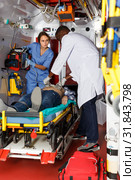 serious afro paramedical using defibrillator for providing medical care to patient. Стоковое фото, фотограф Яков Филимонов / Фотобанк Лори