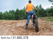 Mototrial rider standing with motorcycle in sand. Extreme sports on motorcross motorbike. Rear view, copyspace. Стоковое фото, фотограф Кекяляйнен Андрей / Фотобанк Лори