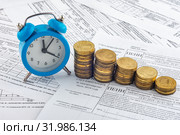 Часы, стопки монет, квитанция с начисленным пени на оплату электроэнергии. Стоковое фото, фотограф Иванов Алексей / Фотобанк Лори