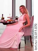 Beautiful slim blonde in a long white with a pink tint from the lighting of the dress at a party. Стоковое фото, фотограф katalinks / Фотобанк Лори