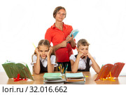 Скучающие школьницы за партой, на заднем плане учитель с тетрадками. Стоковое фото, фотограф Иванов Алексей / Фотобанк Лори