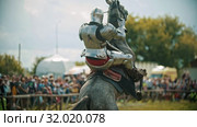 A man knight riding a horse around the battlefield and people watching behind him the fence - the horse rears up. Стоковое видео, видеограф Константин Шишкин / Фотобанк Лори