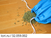 Green mung bean in blue reusable package on wooden background. Eco packaging concept. Стоковое фото, фотограф Ольга Балынская / Фотобанк Лори