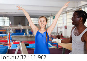 African male coach and teenage girl exulting sporting achievements at acrobatic hall. Стоковое фото, фотограф Яков Филимонов / Фотобанк Лори