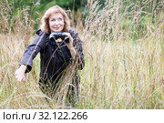 Mature woman with binoculars in high grass, bird watcher, copy space. Стоковое фото, фотограф Кекяляйнен Андрей / Фотобанк Лори