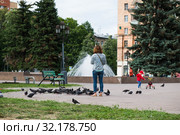 Женщина-мать кормит голубей, а ребенок катается на трехколесном велосипеде (2019 год). Редакционное фото, фотограф Кузин Алексей / Фотобанк Лори