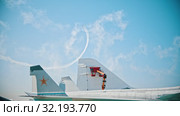 Reactive planes flying in the sky and performing pirouettes leaving smoke lines - people painting a part of an airplane on the foreground. Стоковое видео, видеограф Константин Шишкин / Фотобанк Лори