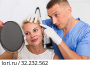 Specialist is analysing skin of female patient with using mirror before the procedure. Стоковое фото, фотограф Яков Филимонов / Фотобанк Лори