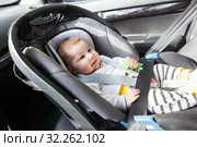 Happy, smiling baby lying in child safety seat on front passenger seat, fasten with belt, age from 0 to 6 month. Стоковое фото, фотограф Кекяляйнен Андрей / Фотобанк Лори