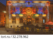 People relax in bar in central square in Paola during celebration of Christmas in Malta (2018 год). Редакционное фото, фотограф Kira_Yan / Фотобанк Лори