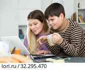 Young woman working at laptop with small son indoors. Стоковое фото, фотограф Яков Филимонов / Фотобанк Лори