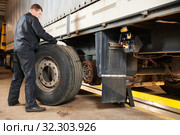 Truck repair service. Mechanic works with tire in truck workshop. Стоковое фото, фотограф Дмитрий Калиновский / Фотобанк Лори