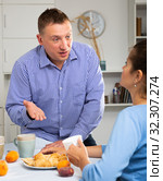 Upset man and frustrated woman arguing at home kitchen. Focus on woman. Стоковое фото, фотограф Яков Филимонов / Фотобанк Лори