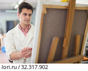 Man near easel painting on canvas. Стоковое фото, фотограф Яков Филимонов / Фотобанк Лори