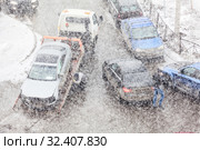 Tow truck lifting broken car from crossroad after road crash. Heavy snowfall. Unrecognizable persons. Стоковое фото, фотограф Кекяляйнен Андрей / Фотобанк Лори