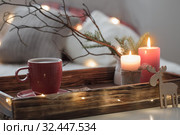 Red cup of tea on tray with burning candles on background sofa with pillows. Cozy home concept. Стоковое фото, фотограф Майя Крученкова / Фотобанк Лори