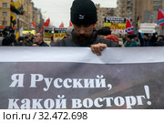 Участник Русского марша на улице Маршала Бирюзова держит баннер в городе Москве, Россия 4 ноября 2019. Редакционное фото, фотограф Николай Винокуров / Фотобанк Лори