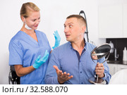 Patient is analysing his skin with using mirror after the procedure. Стоковое фото, фотограф Яков Филимонов / Фотобанк Лори
