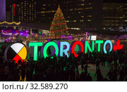 TORONTO, CANADA 12 23 2018: Night view on Nathan Phillips square in the major Canadian city Toronto with people having fun on the skating rink in front of TORONTO sign and Christmas tree. Редакционное фото, фотограф Вадим Роднев / Фотобанк Лори