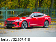 Красный автомобиль KIA Стингер у решетки Петровского парка октябрьским днем. Кронштадт (2019 год). Редакционное фото, фотограф Виктор Карасев / Фотобанк Лори