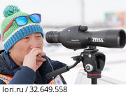 Coach of South Korea biathlon team watches biathletes in monocle at shooting range of biathlon stadium. Junior biathlon competitions East of Cup (2019 год). Редакционное фото, фотограф А. А. Пирагис / Фотобанк Лори