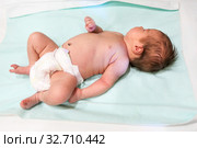 Newborn Caucasian baby lying on treatment couch with disposable diaper on body. Стоковое фото, фотограф Кекяляйнен Андрей / Фотобанк Лори