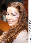 Curly hair woman with painted flowers of face skin, portrait, looking at camera. Стоковое фото, фотограф Кекяляйнен Андрей / Фотобанк Лори