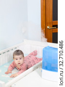 Air humidifying in children room, baby girl lying in white crib with humidifier in use next to bed. Стоковое фото, фотограф Кекяляйнен Андрей / Фотобанк Лори