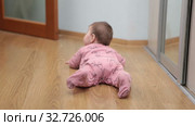 Six month old baby crawling on floor then turning on belly, rear view. Стоковое видео, видеограф Кекяляйнен Андрей / Фотобанк Лори