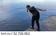 Teenage girl preparing to jump water fro pier, dressed rubber diving suit. Стоковое видео, видеограф Кекяляйнен Андрей / Фотобанк Лори