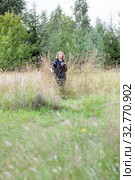 Birds watcher hidden in dry grass, mature woman with binoculars in hand, natural scientist. Стоковое фото, фотограф Кекяляйнен Андрей / Фотобанк Лори