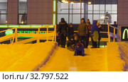 Дети катаются с ледяной горки на городской площади. Children ride on an ice slide in the town square. (2019 год). Редакционное видео, видеограф Евгений Романов / Фотобанк Лори