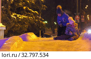 Дети катаются с ледяной горки на городской площади. Children ride on an ice slide in the town square. (2019 год). Редакционное видео, видеограф Евгений Романов / Фотобанк Лори