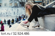 A young woman with blond hair tie up her figure skates before walking out on the rink. Стоковое видео, видеограф Константин Шишкин / Фотобанк Лори