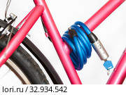 Simple cable lock with padlock is on pink bike frame, white background. Стоковое фото, фотограф Кекяляйнен Андрей / Фотобанк Лори