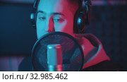 A man in hoodie rapping through the pop-filter in the microphone. Стоковое видео, видеограф Константин Шишкин / Фотобанк Лори